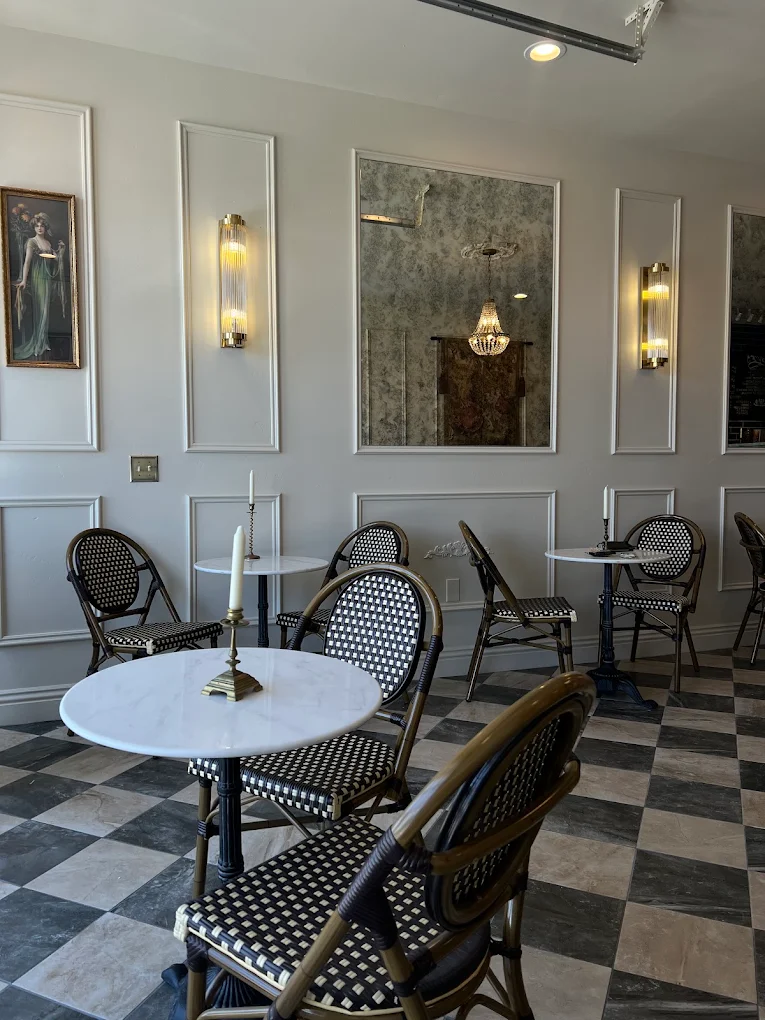 Antique mirrors, brass sconces and candlelit marble tables along the molded ivory wall at Creperie Antoinette