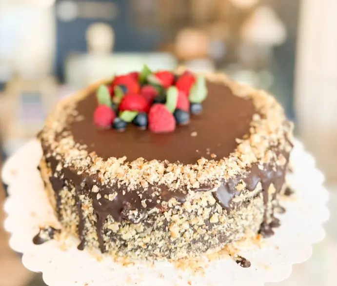 A chocolate cake topped with fresh berries and chopped nuts at Creperie Antoinette