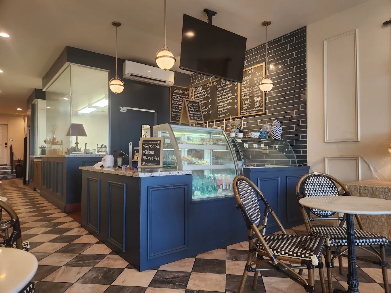 The navy counter with pastry and gelato cases, chalkboard crêpe and espresso menus on charcoal subway tile