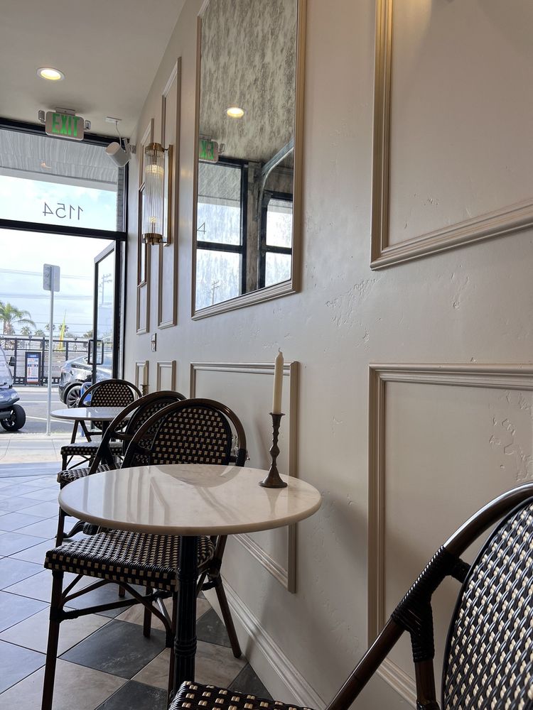 Marble bistro tables by the front window at Creperie Antoinette, with brass sconces, mirrors and Garnet Avenue outside