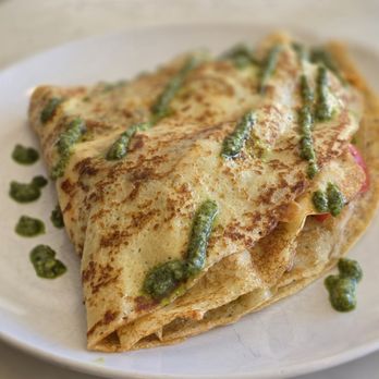 A folded savory crêpe with pesto drizzle on a white plate at Creperie Antoinette