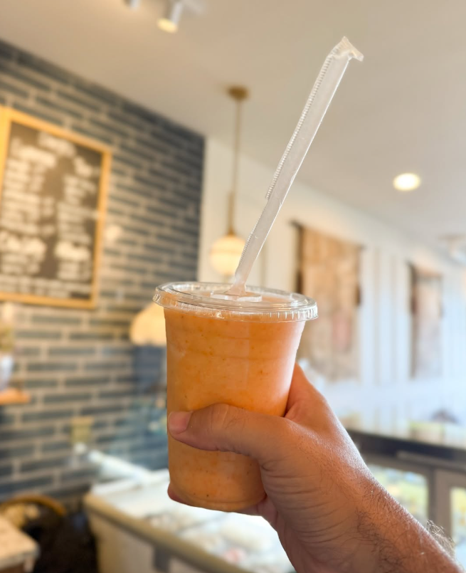 A fresh orange smoothie in a clear cup inside the café